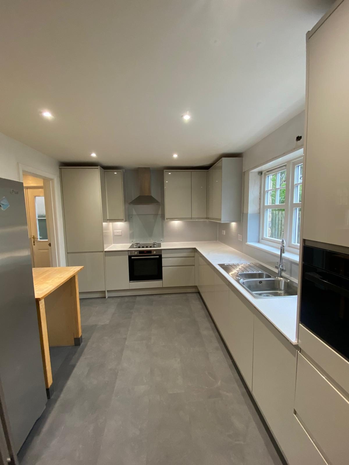 Grey handleless kitchen with integrated appliances and a window