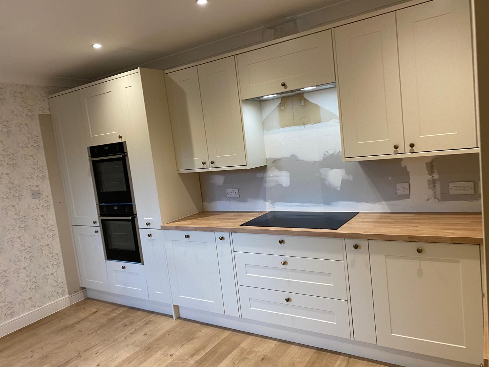 White shaker kitchen with oak worktop and tiled splashback